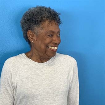 African-american woman standing against a blue background smiling