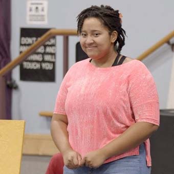 High school aged girl in pink sweater standing shyly