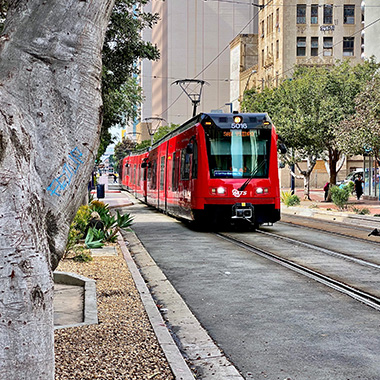 Red MTS Trolley on tracks in downtown San Diego