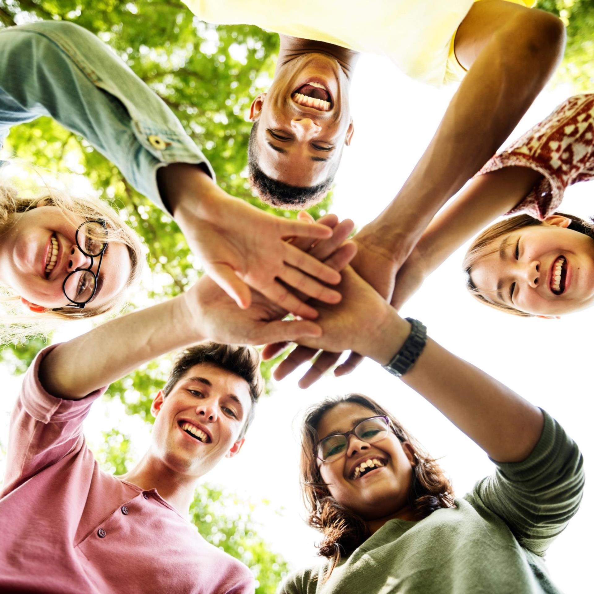 Youth standing in a circle with their hands piled in together