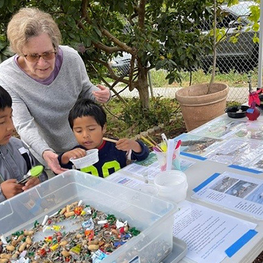 1x1 Oceanside Garden Crown Heights volunteer shows 2 young boys seeds