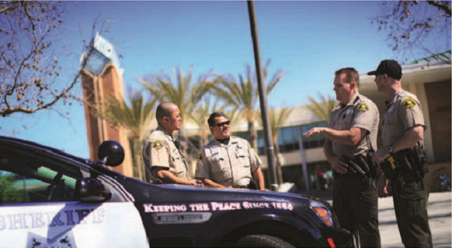 Sherriff's officers standing next to police car